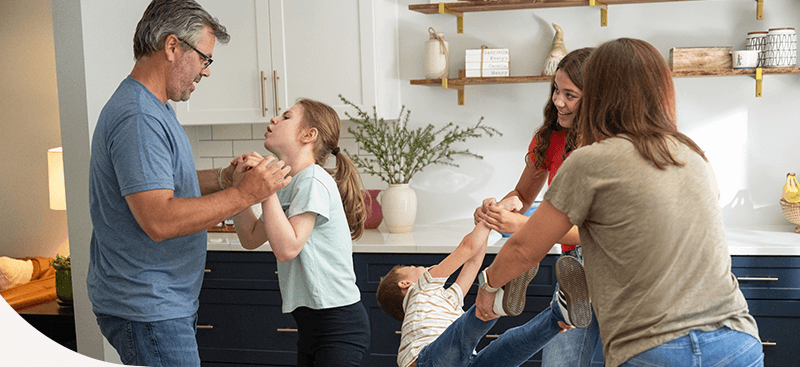 Evie playing with her family in their kitchen