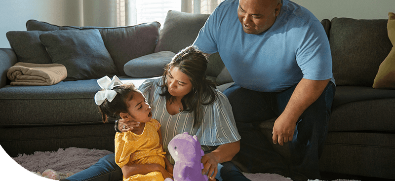 Gigi playing with a stuffed dinosaur with her family