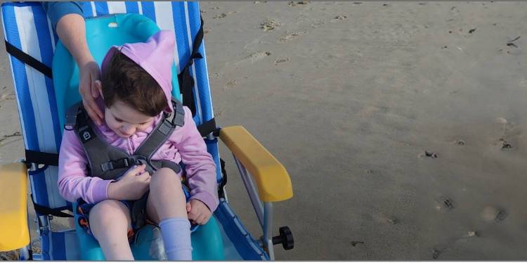 Lina sits in a chair on the beach
