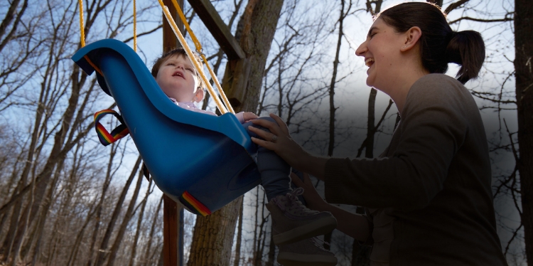 Diana pushing Lina on a swing outdoors