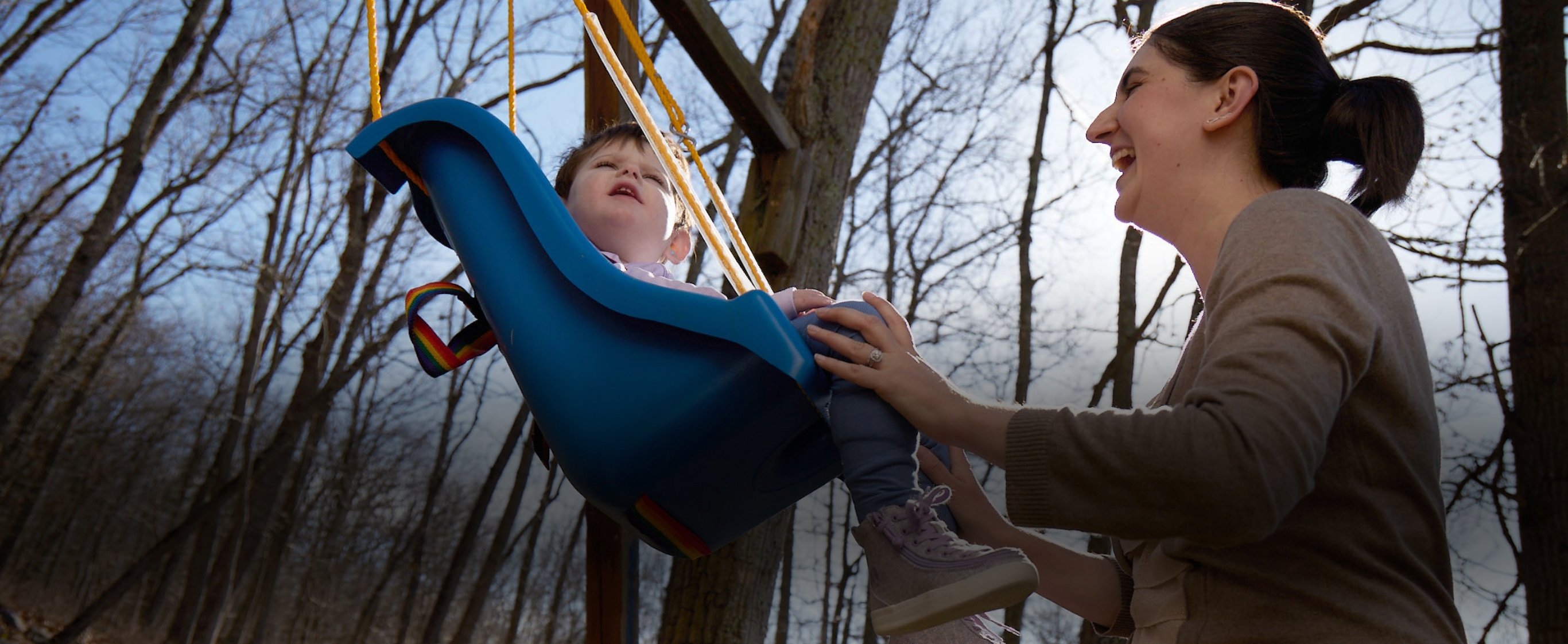 Diana pushing Lina on a swing outdoors