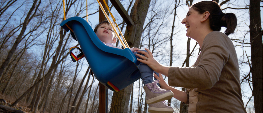 Diana pushing Lina on a swing outdoors