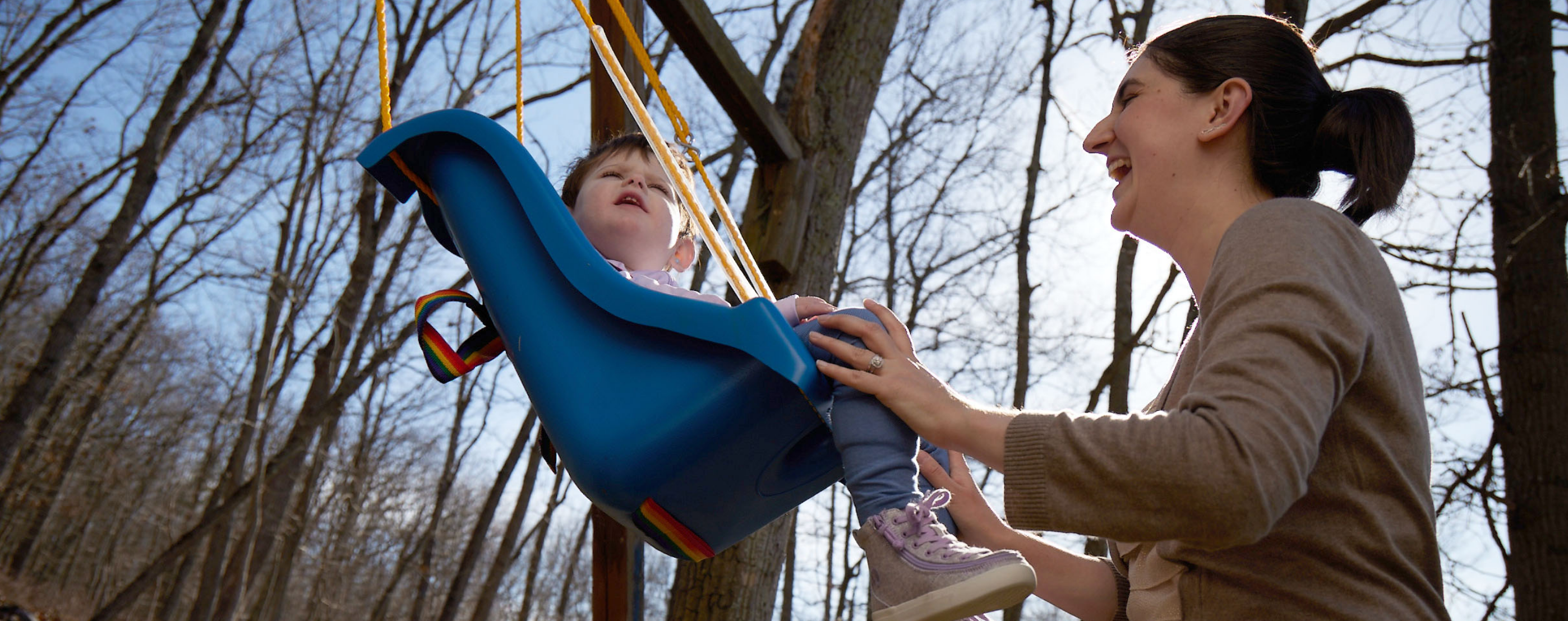 Diana pushing Lina on a swing outdoors