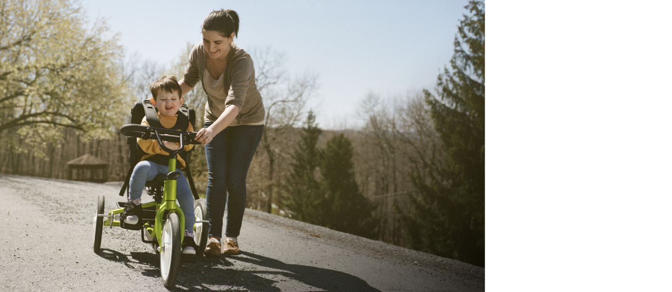 Diana steadies Lina as she rides a tricycle